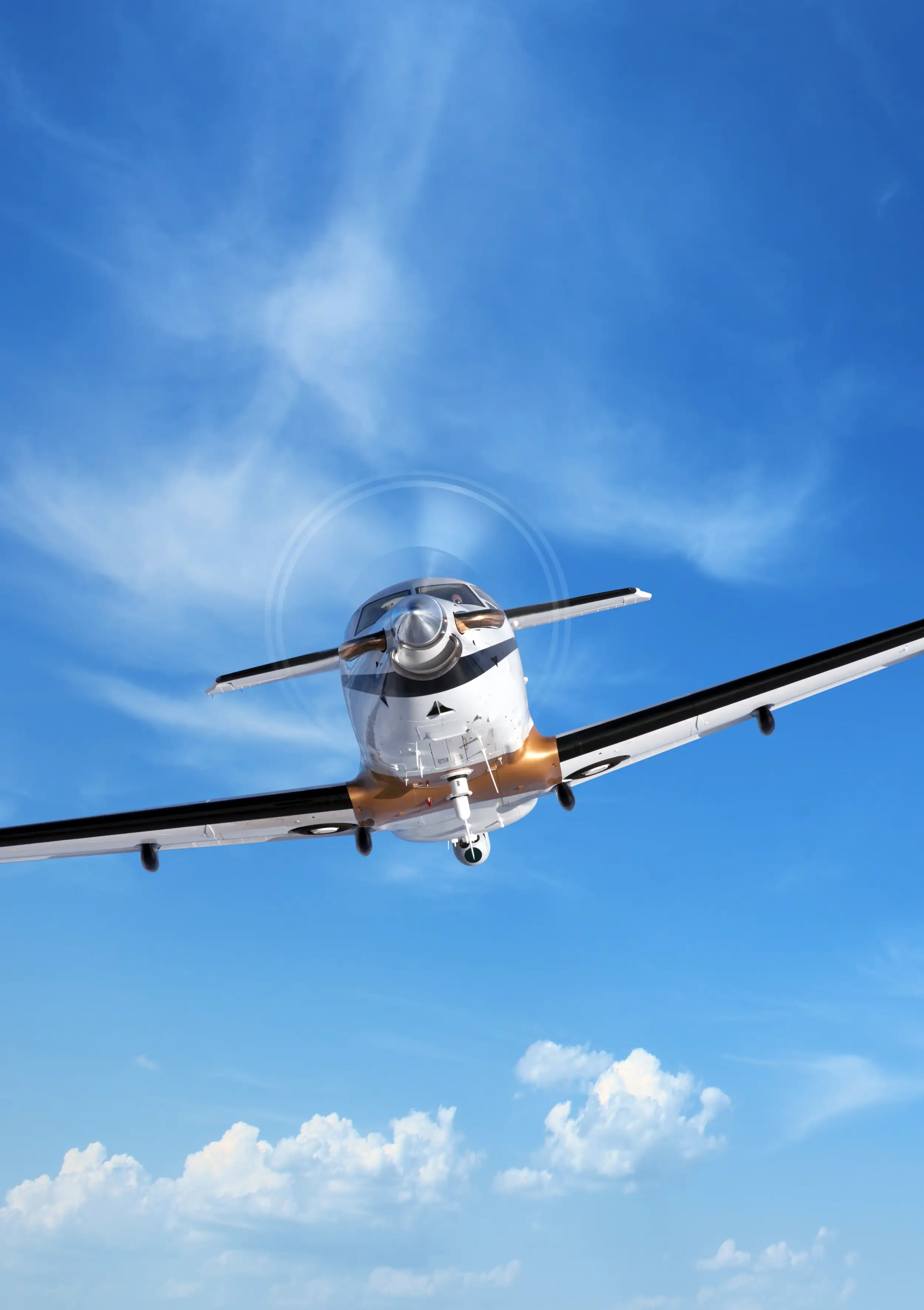 A PC-12 Spectre, photographed from below, flies through the blue sky.