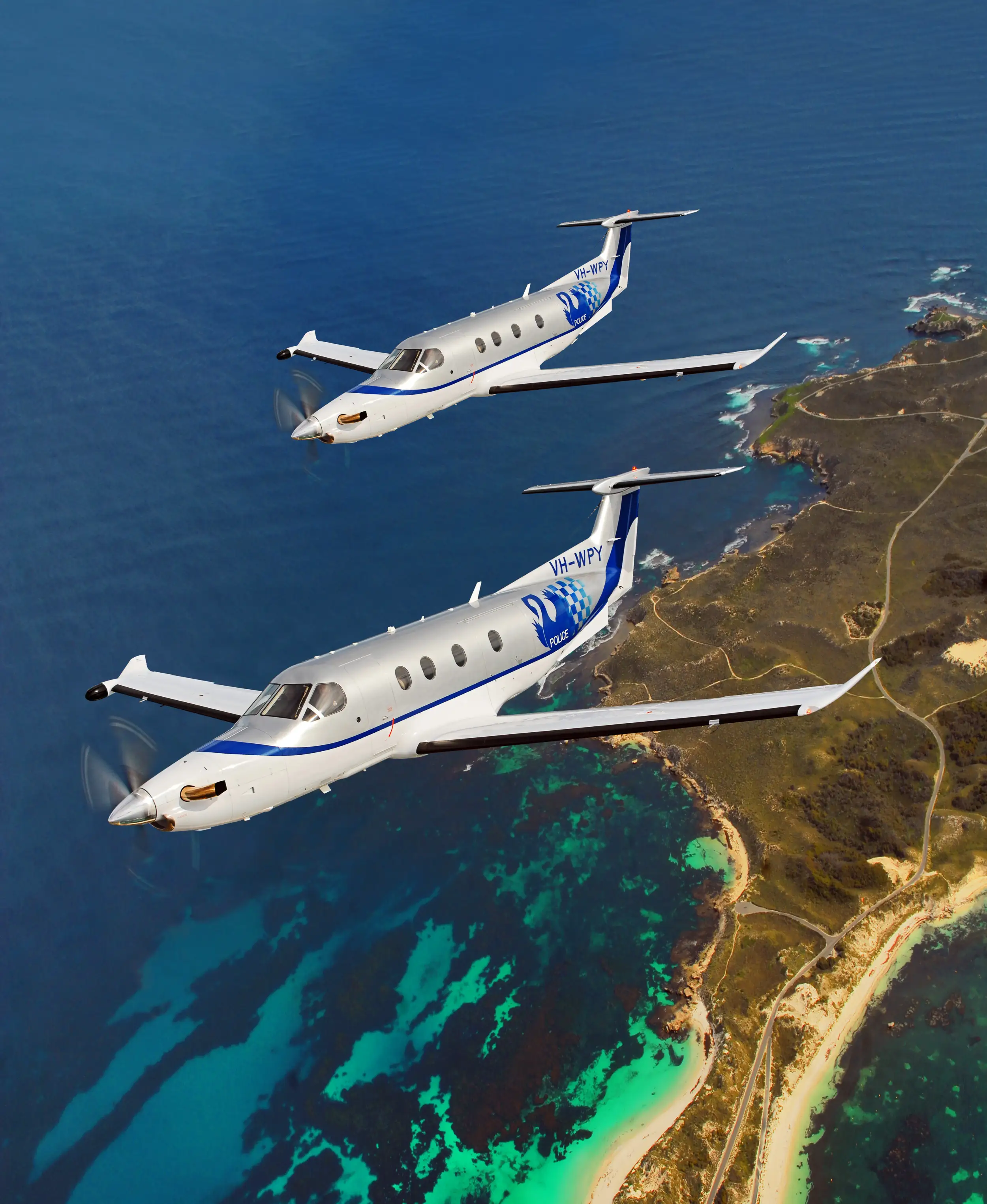 A PC-12 of the Western Australia Police flies over water and an island.