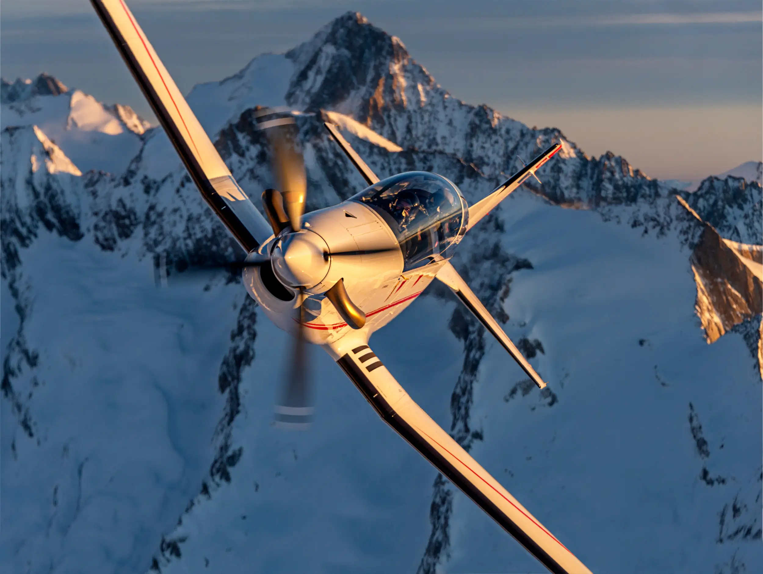 A PC-7 MKX flies over mountains